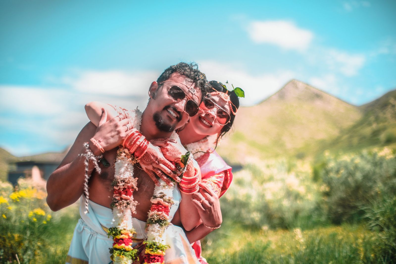 A newly married couple laughing together in a sunlit meadow